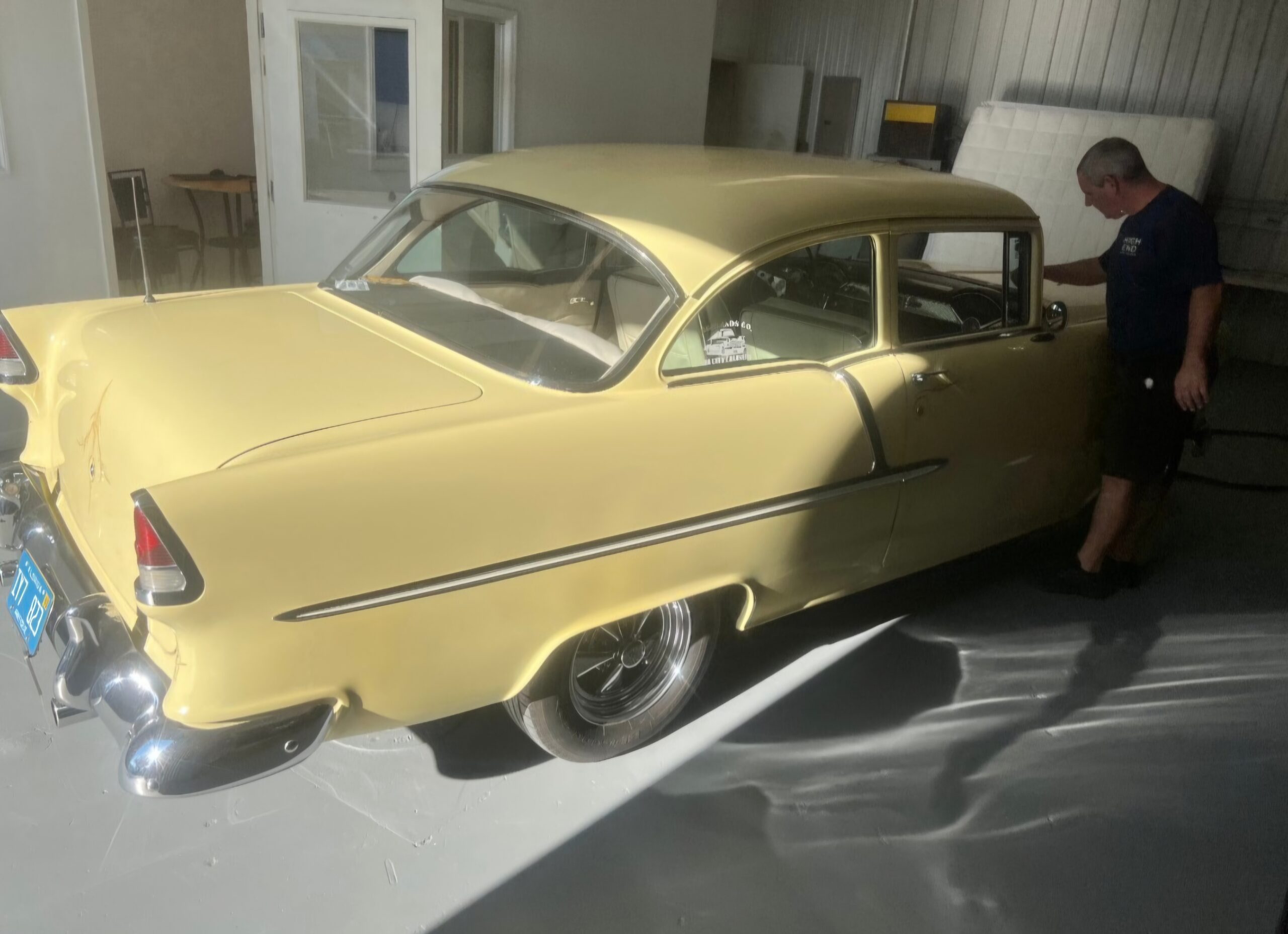 yellow car parked in a bay and a man looking at the passenger side door. He is looking for auto glass damage.